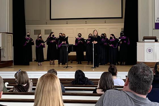 Photo showing people sitting in the pews in the Chapel, facing the stage with Chatham's choir performing